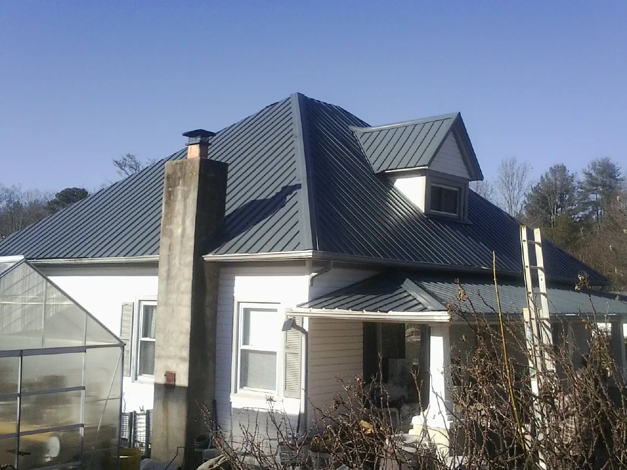 Dark blue standing seam metal roof on a white farmhouse with dormer — Slate & Tile Roof Repair by Roofing Brothers in Mattapoisett