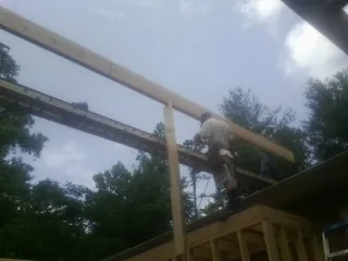 Carpenter setting a ridge beam over a new addition frame — Ice Dam Removal by Roofing Brothers in Mattapoisett