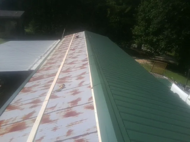 Old rusted panels beside newly installed green metal roofing — Wind Damage Roof Repair by Roofing Brothers in Mattapoisett