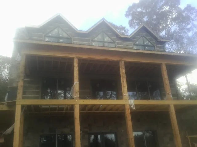 Dormers and porch framing on a large log home under construction — Roof Coating work by our crew in Mattapoisett