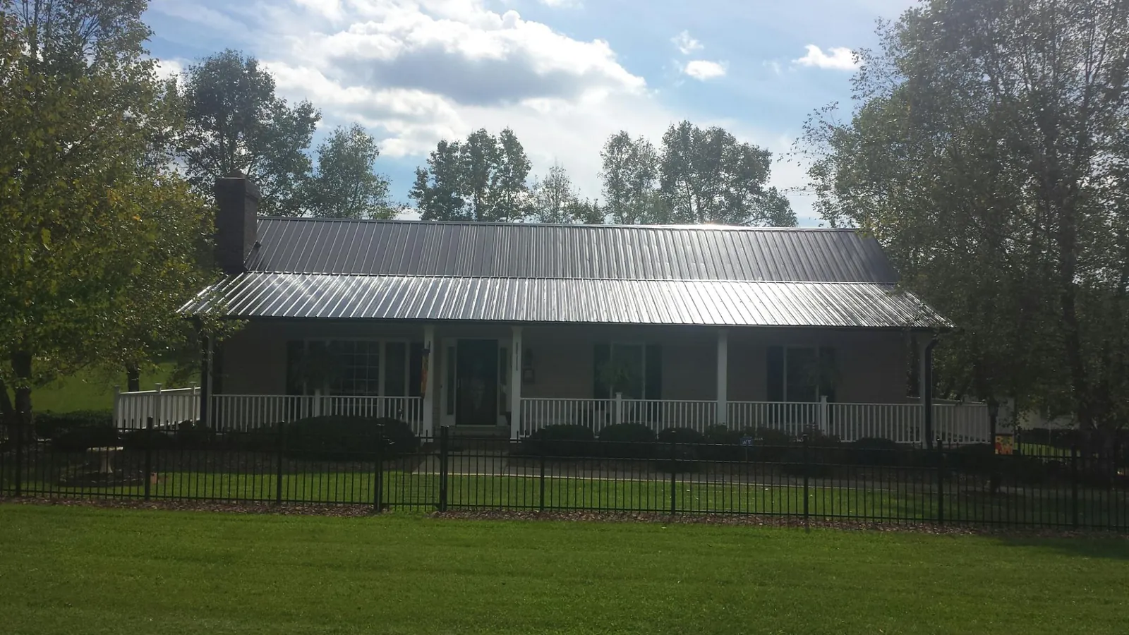 Gray metal roof on a brick ranch with a full width front porch — Gutter Guard Installation work by our crew in Mattapoisett